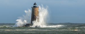 Huge Waves Surround Whaleback Lighthouse as Sun breaks Through Clouds in Maine in New England